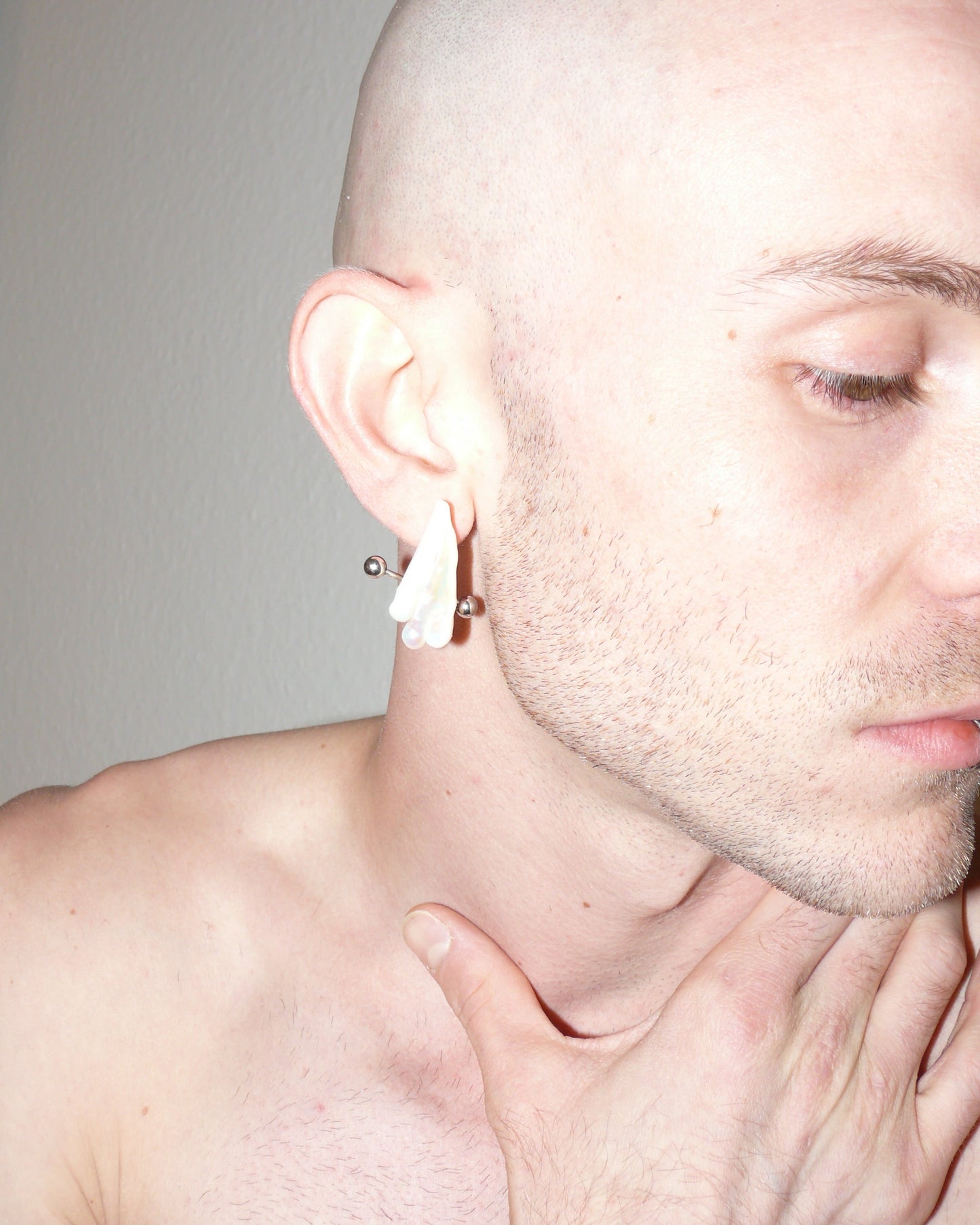 Ghost shaped freshwater pearl earrings with piercing decoration zoomed close up on model right side