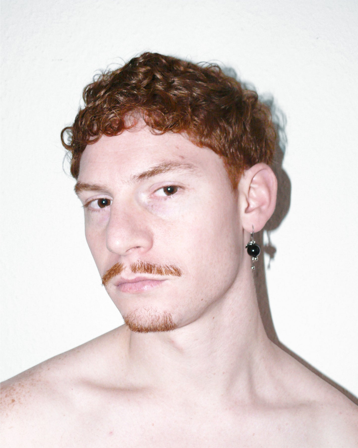 Portrait of model wearing pendant black gemstone earrings with piercing decorations