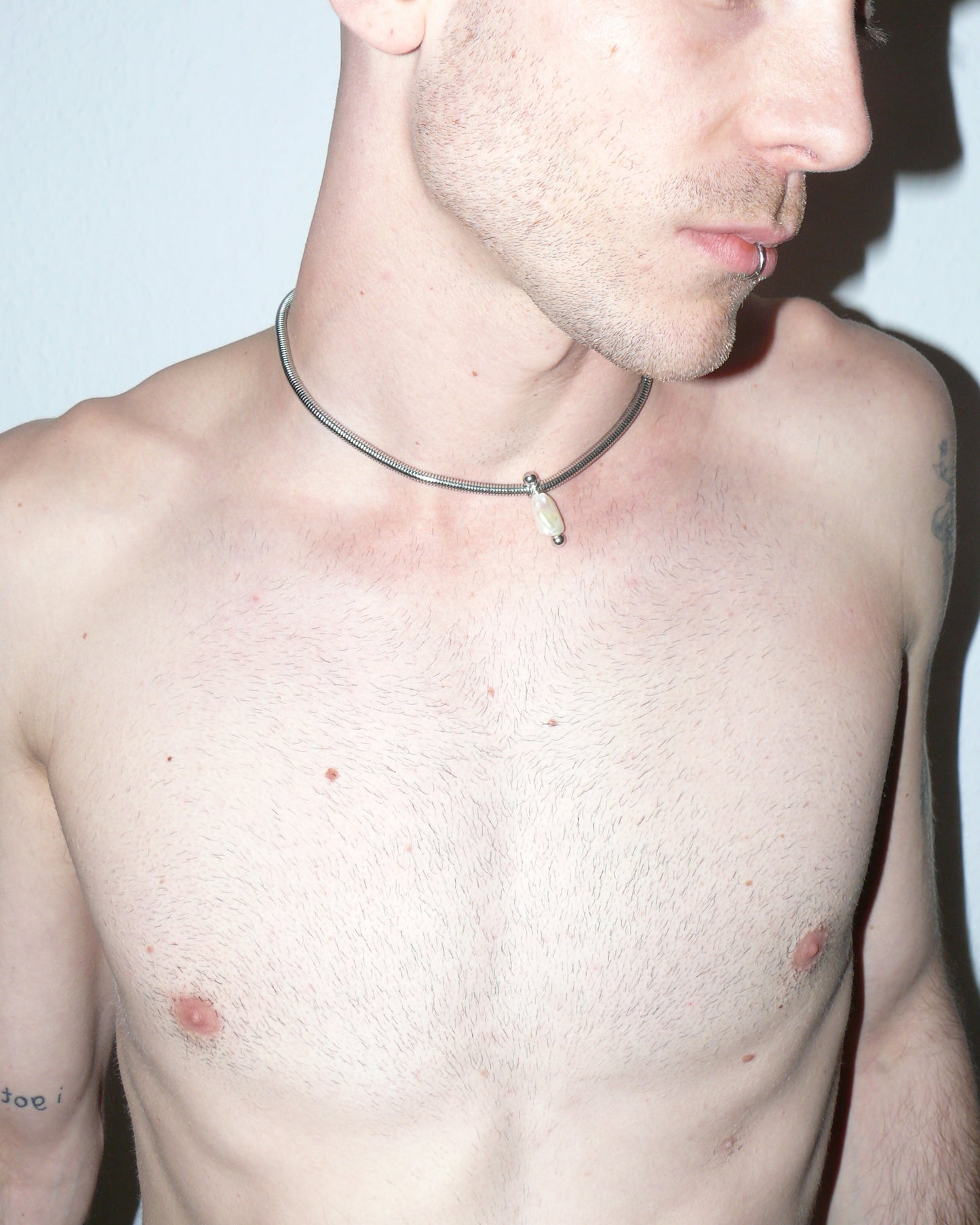 Steel snake chain with pearl pendant decorated with piercing lateral close-up on model