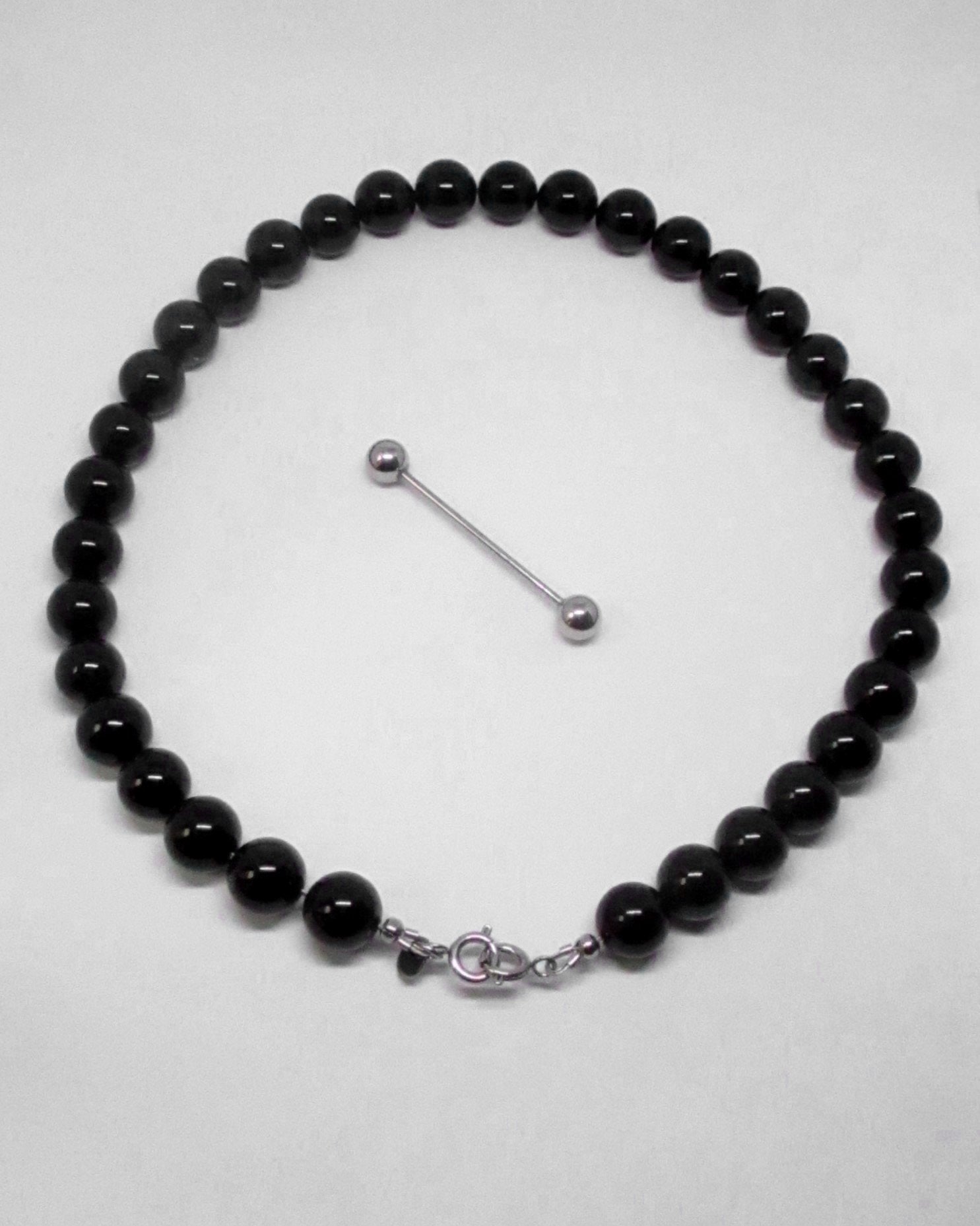 Black beaded necklace with a silver clasp on a white background