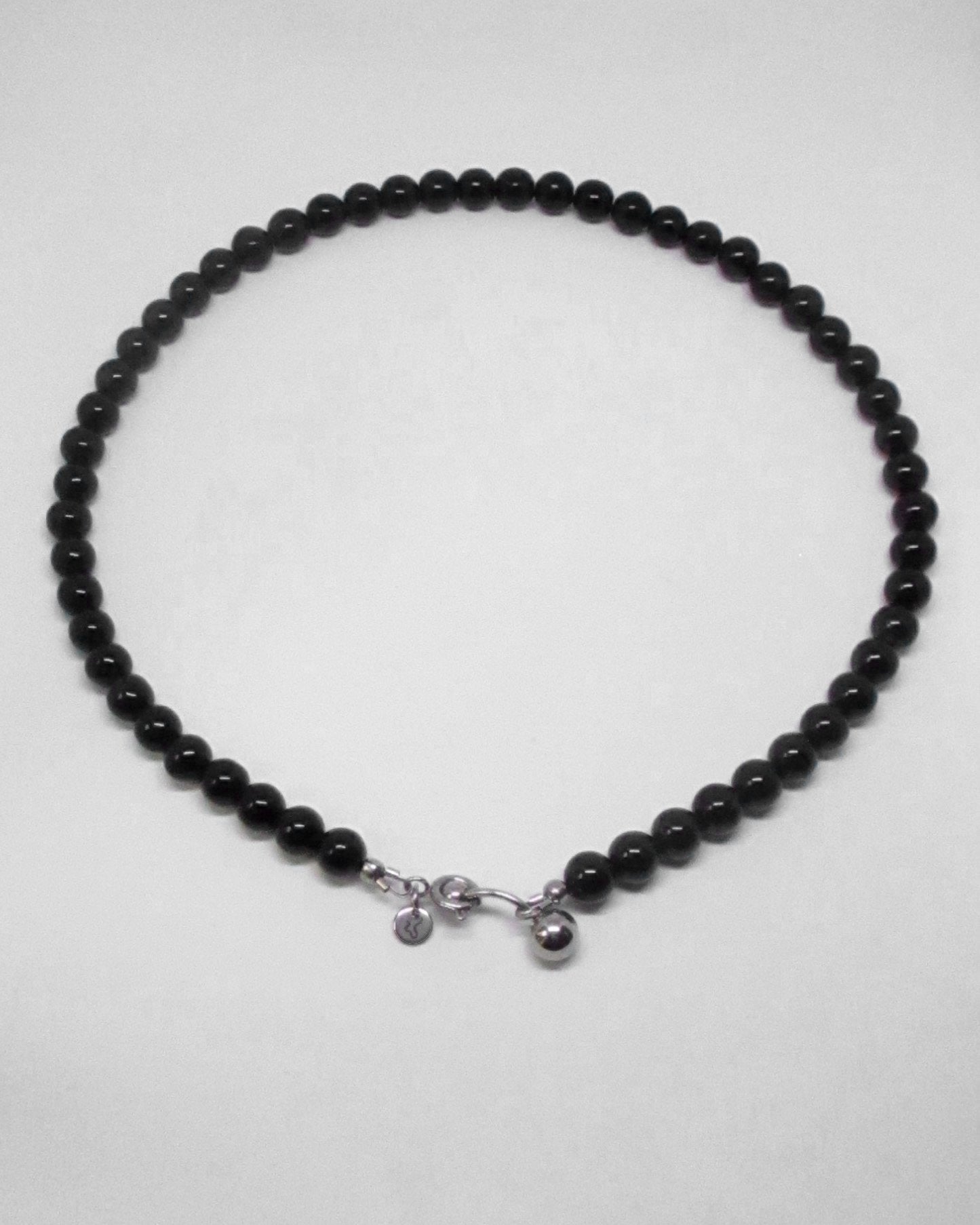 Black beaded necklace with silver charms on a white background