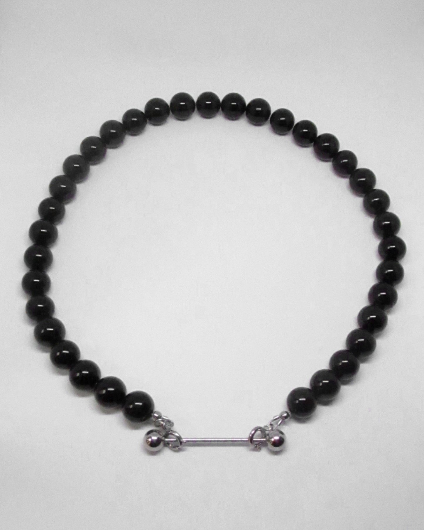 Black beaded necklace with silver clasp on a white background
