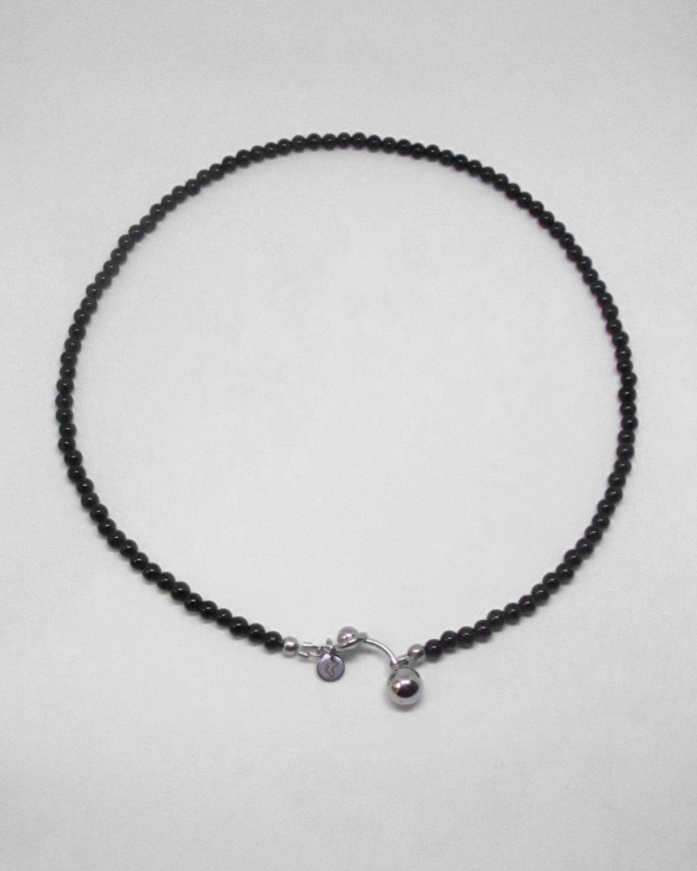 Black beaded necklace with silver piercing clasp on a white background