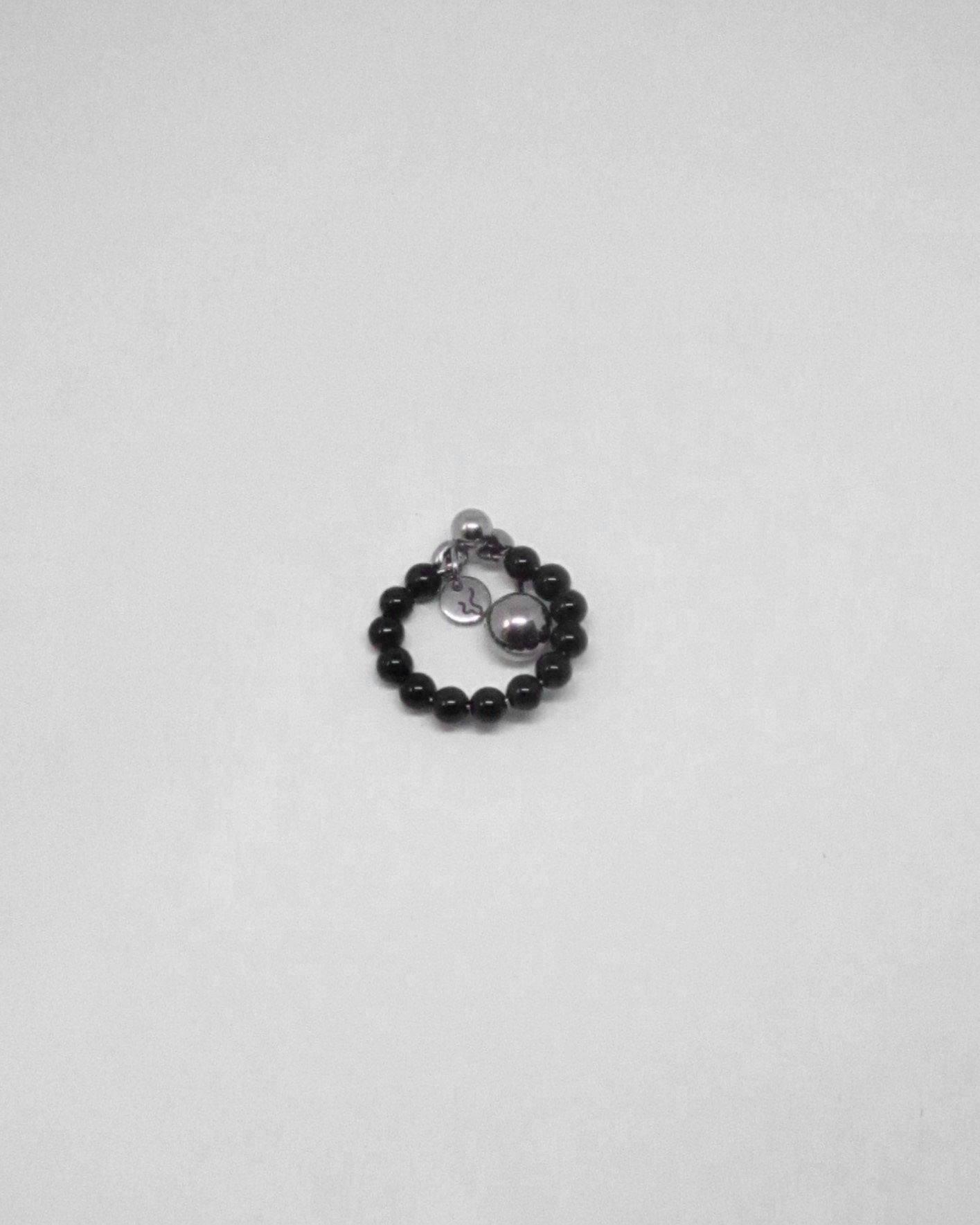 Black beaded ring with silver charms on a white background