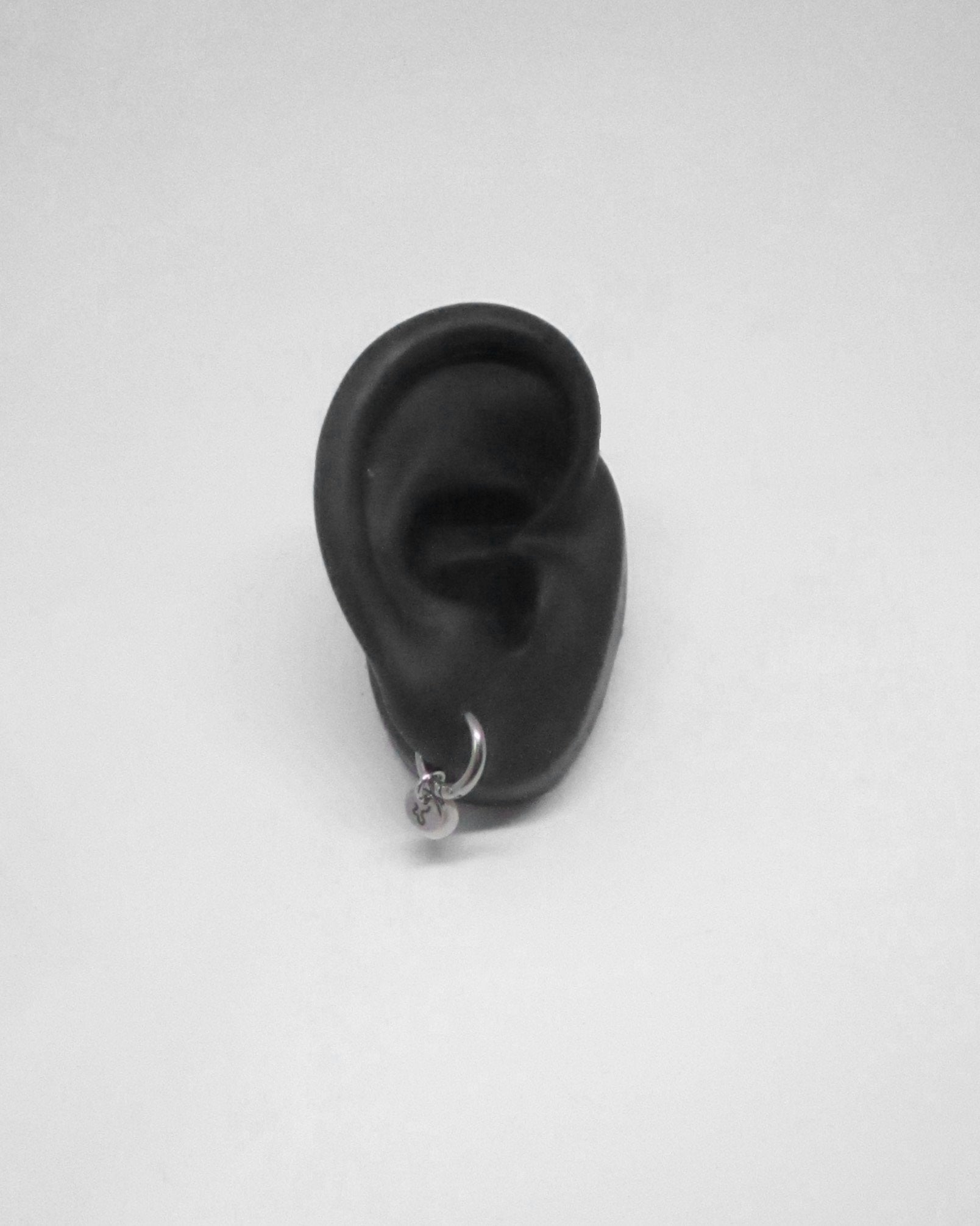 Black silicone ear with a small earring on a white background
