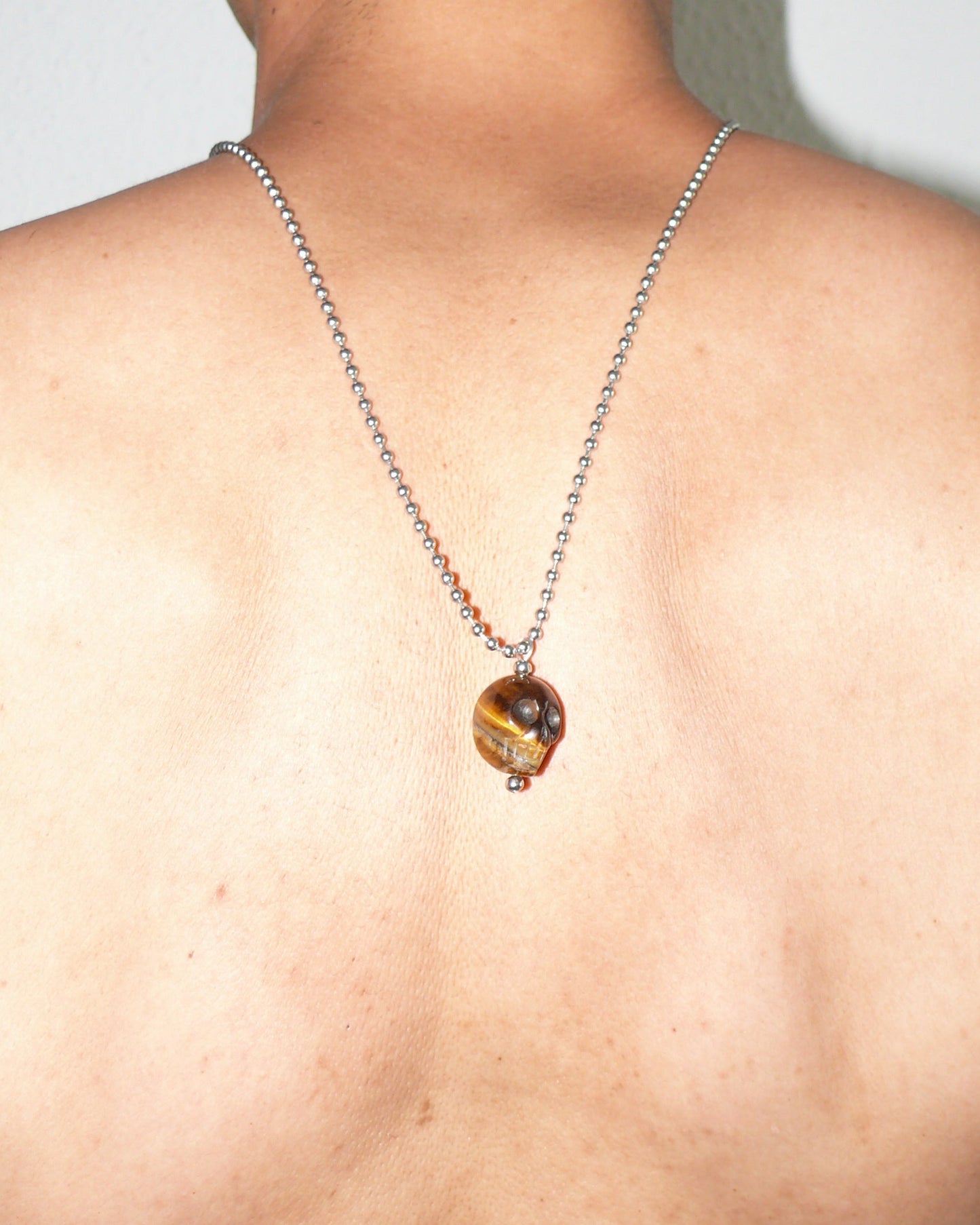 Brown tiger eye agate skull pendant necklace close up on model