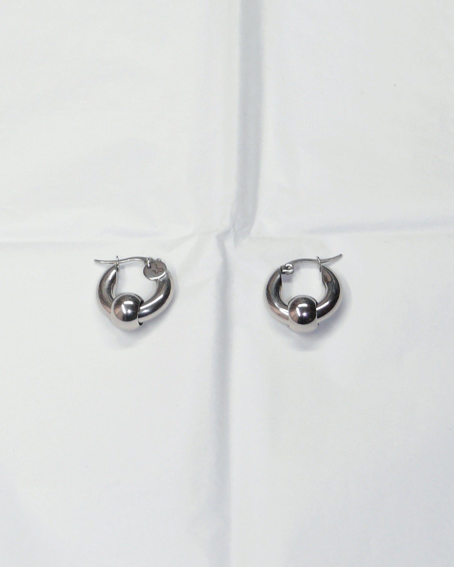 Captive style hoops earrings on folded paper
