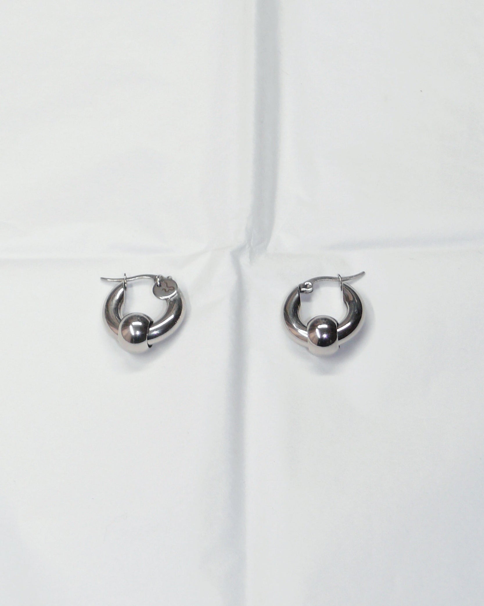 Captive style hoops earrings on folded paper