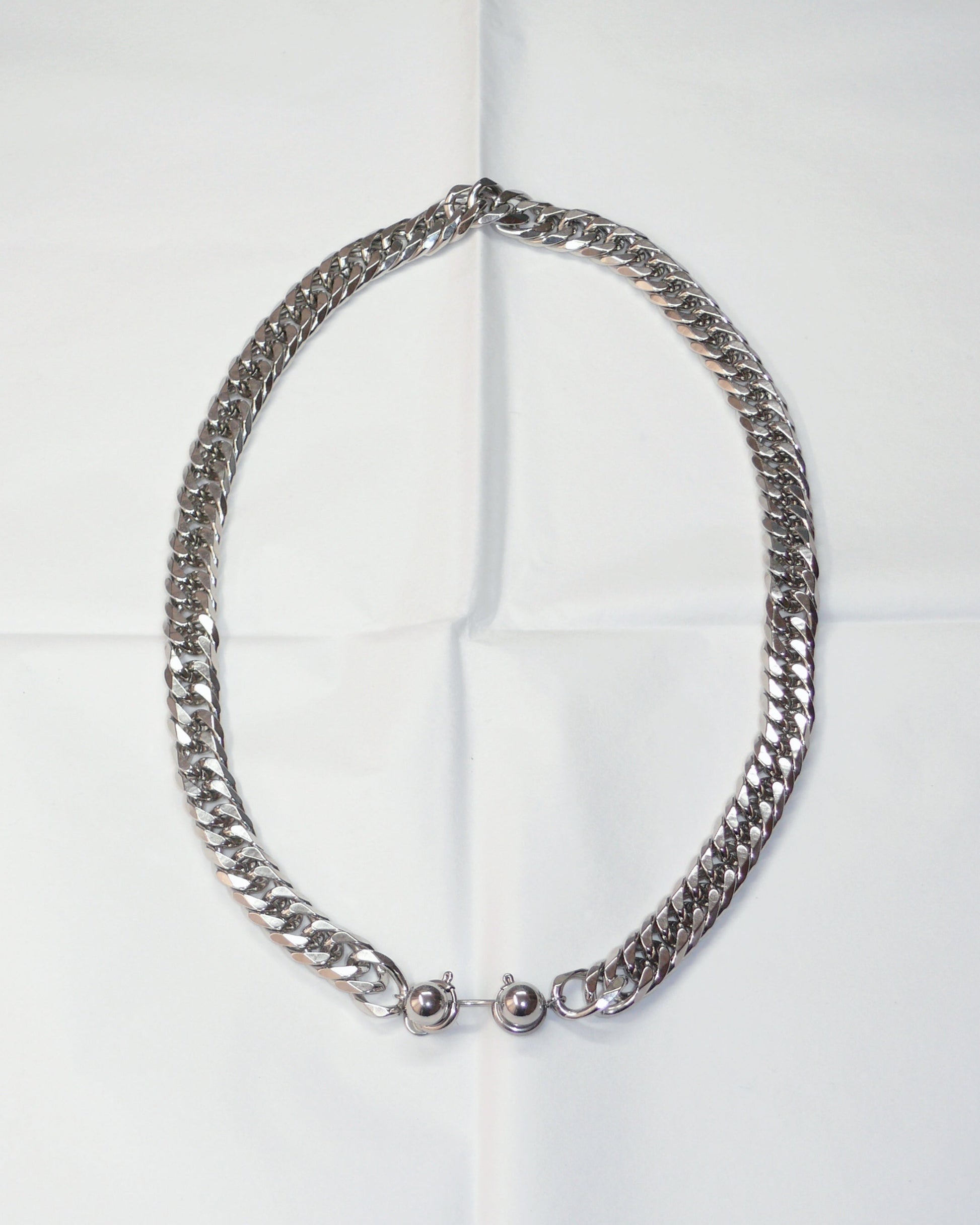 Chunky silver chain necklace with piercing closure on folded paper