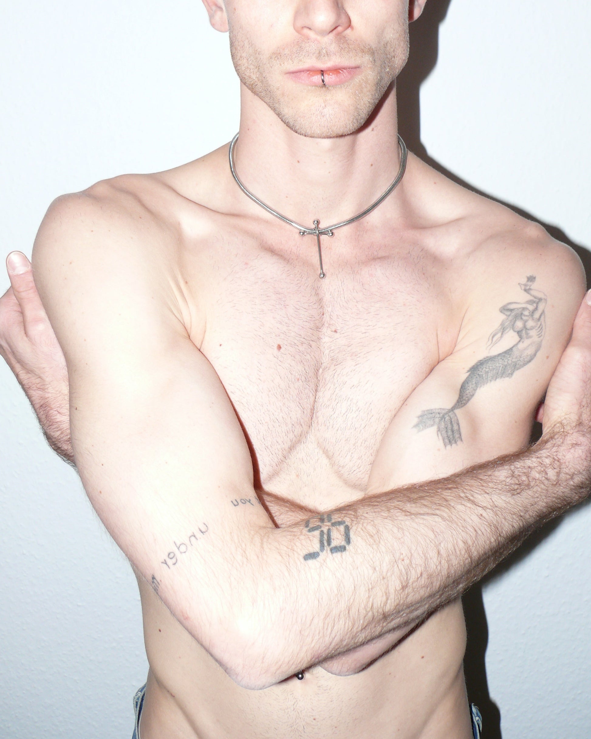 Cross shaped barbells pendant snake steel necklace portrait on model with low crossed arms