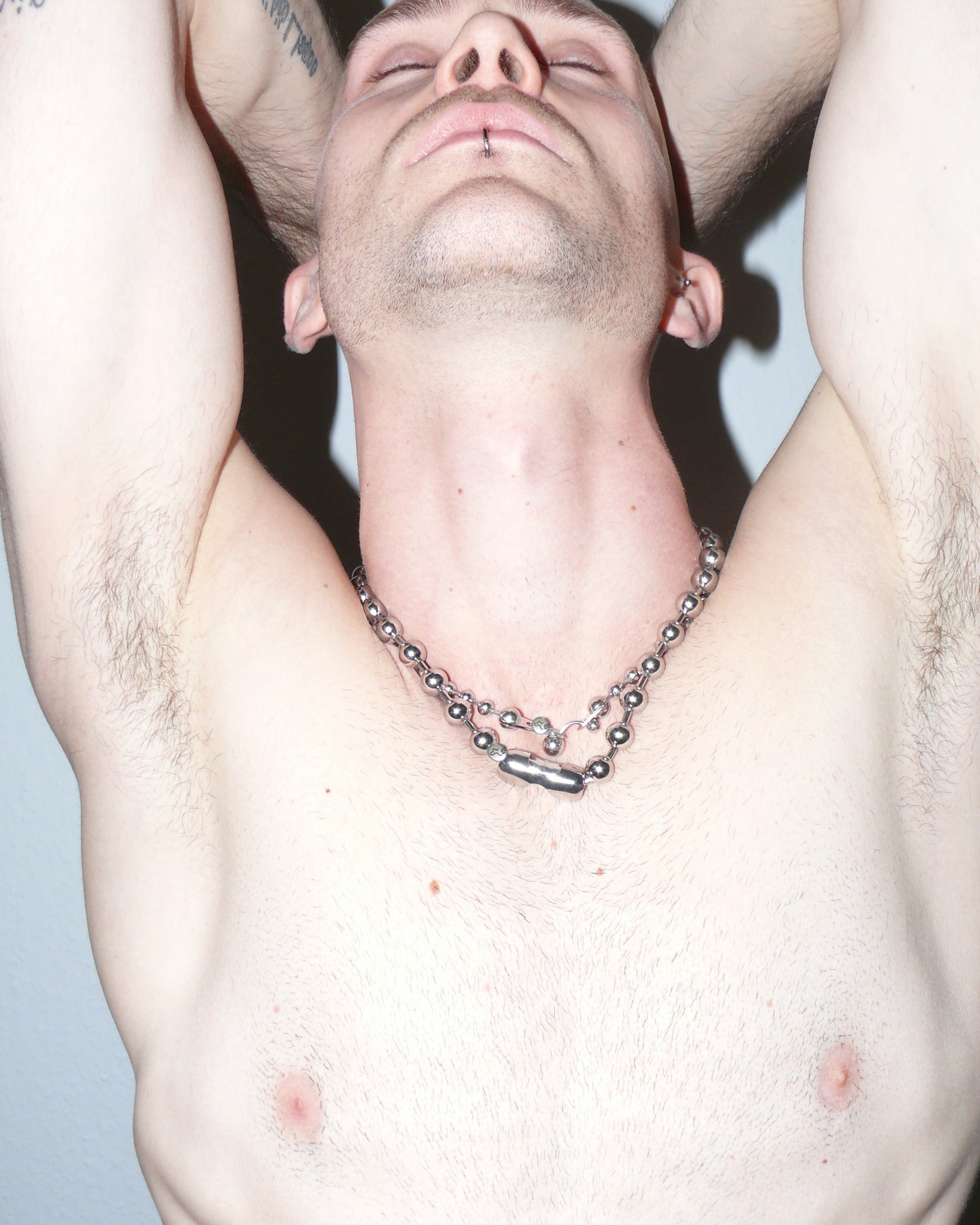 Man with a chain necklace against a light blue background
