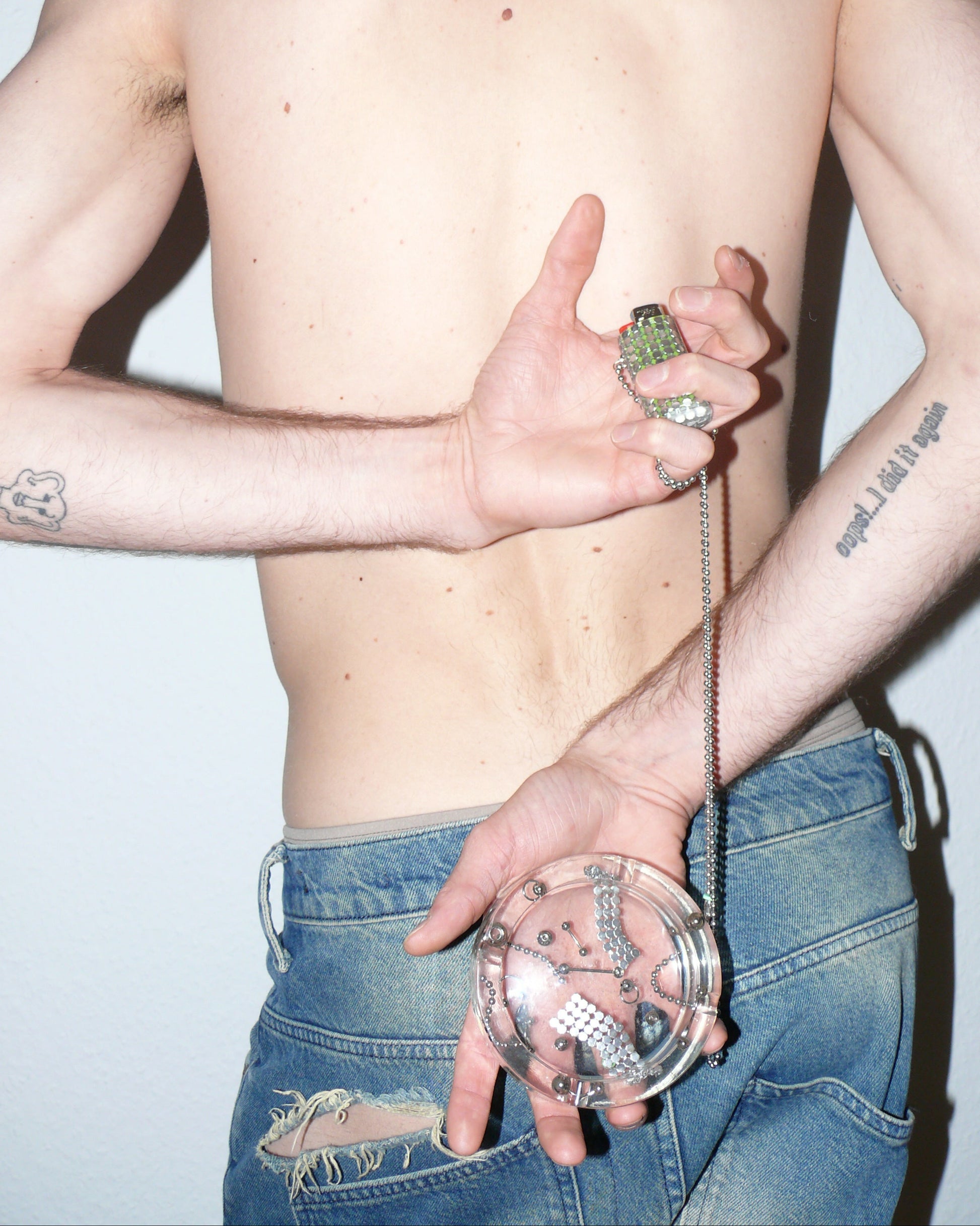 Model holding a resin hastray and lighter necklace, wearing ripped jeans.