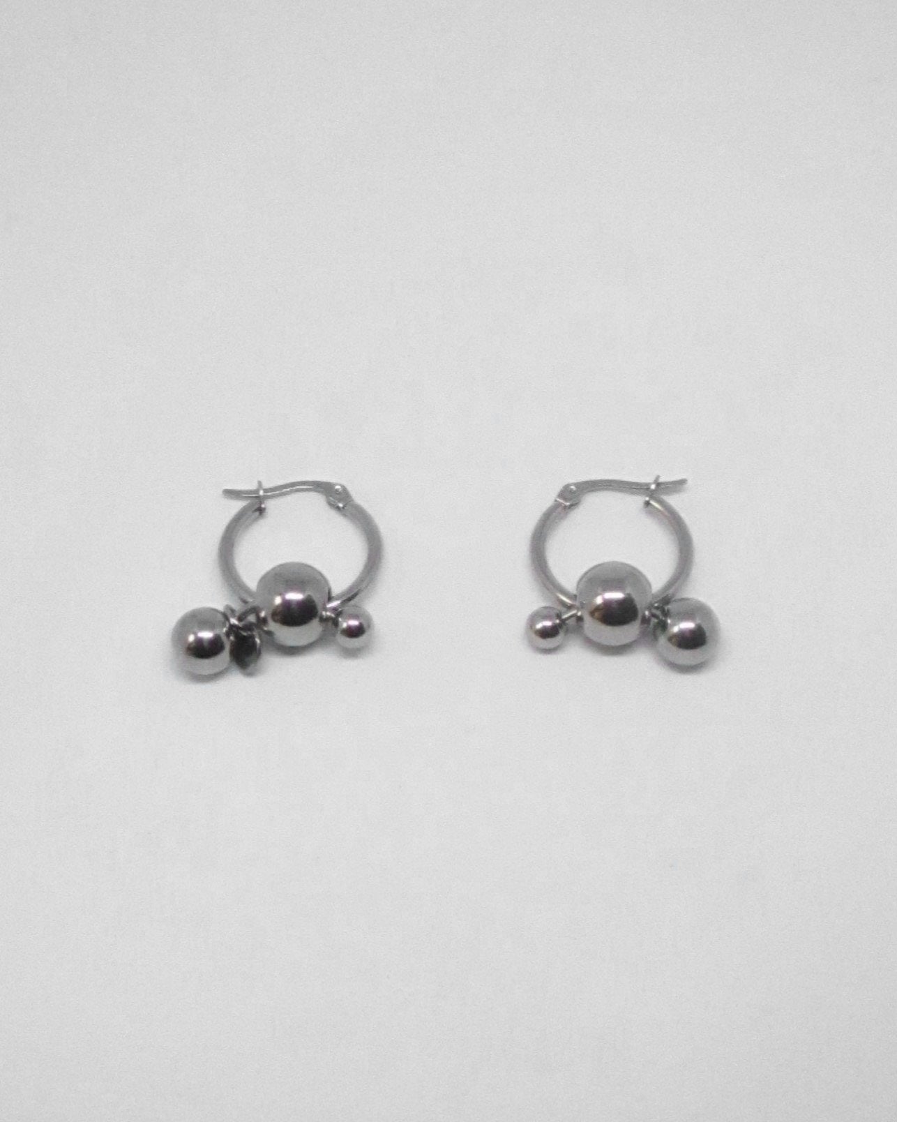 Pair of silver hoop earrings with spherical ends on a light gray background