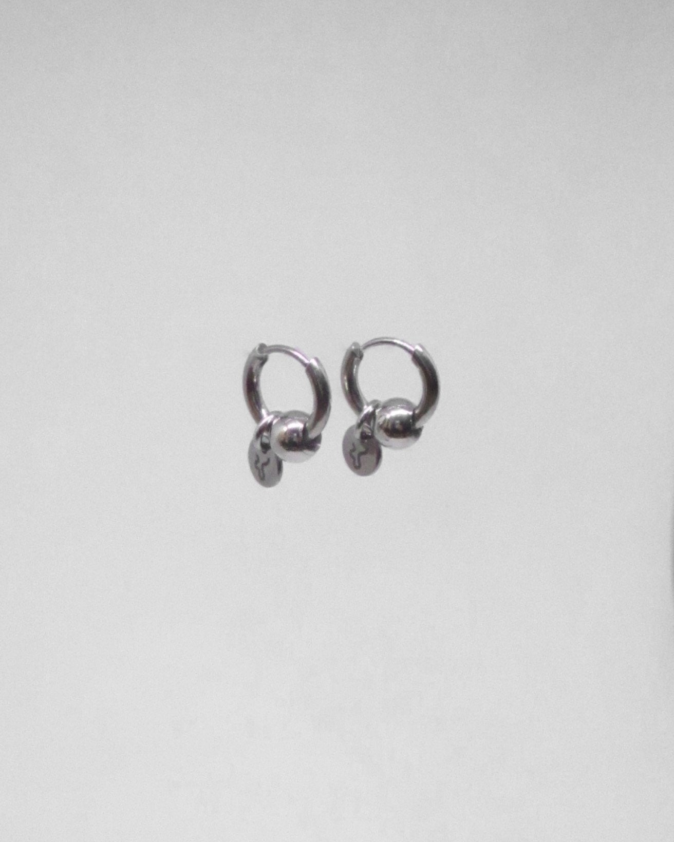 Pair of silver mini hoop earrings on a light gray background