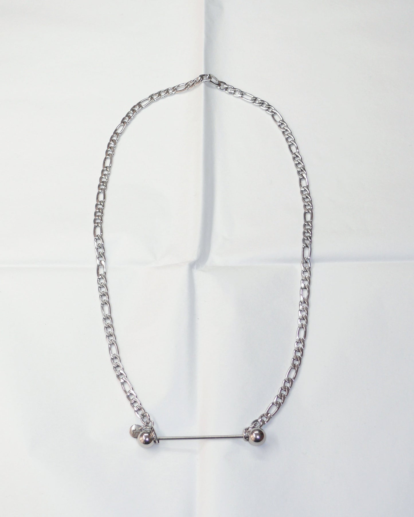 Silver chain necklace with barbell closure on folded paper