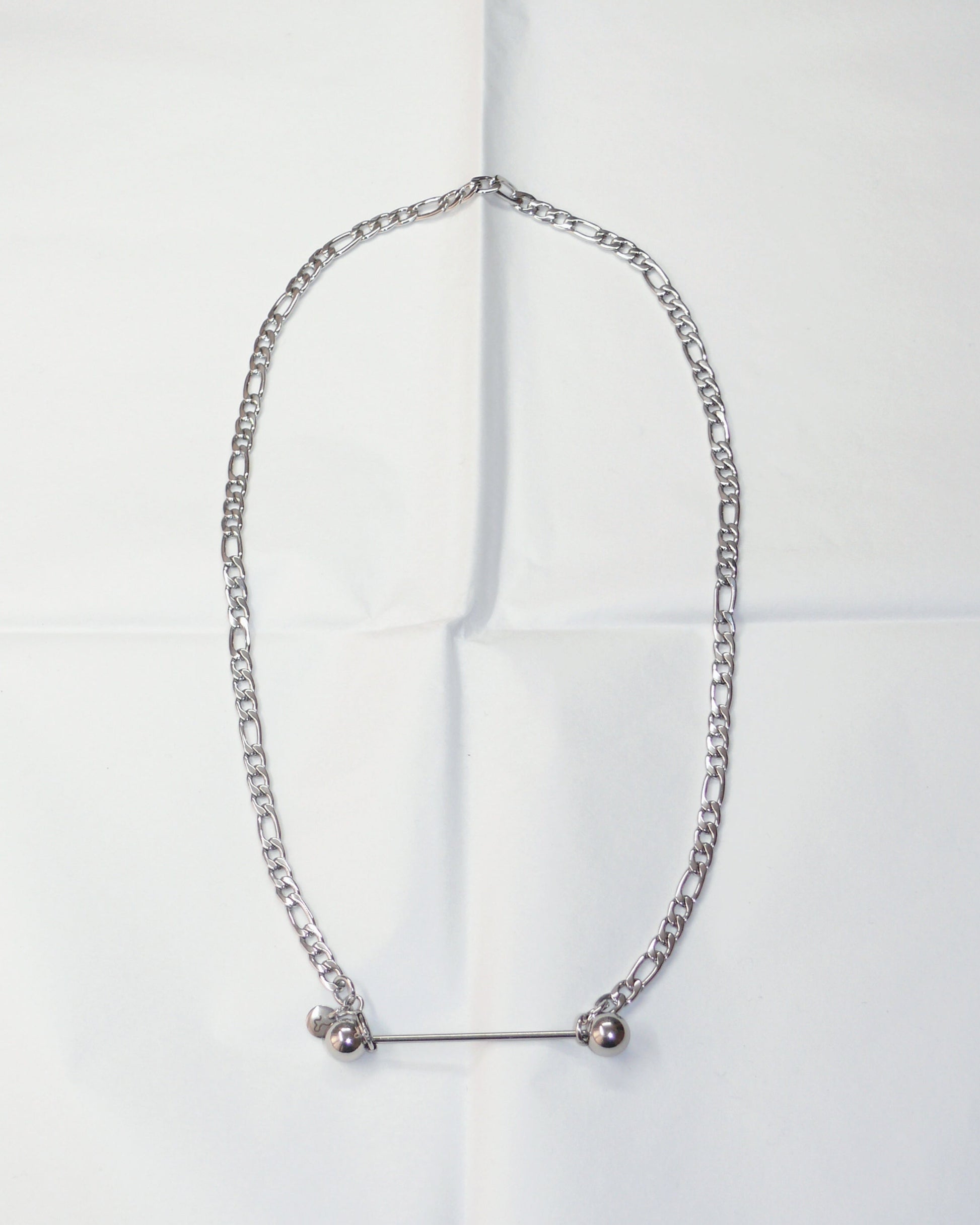 Silver chain necklace with barbell closure on folded paper