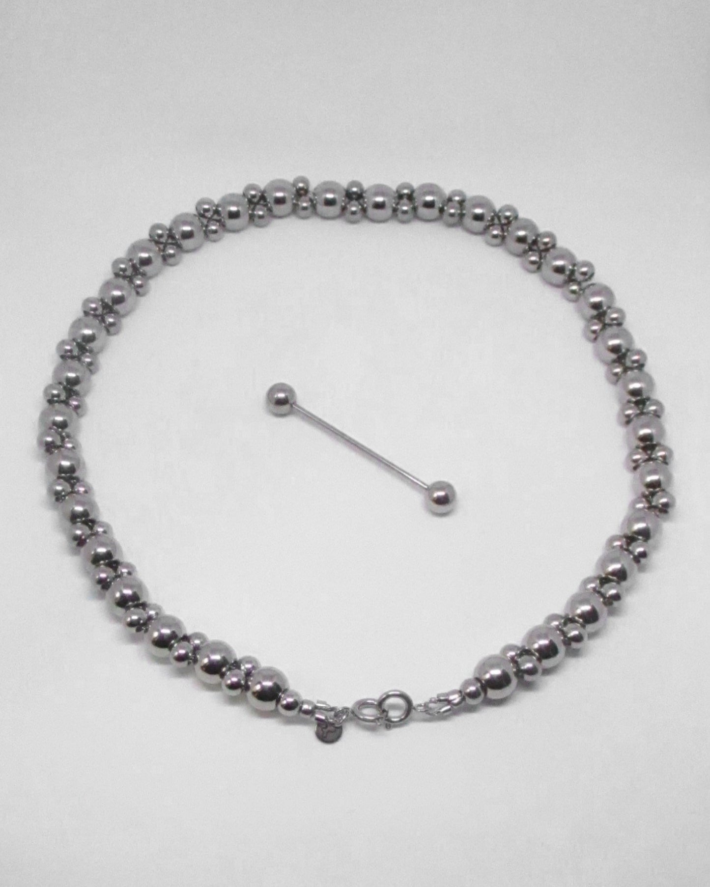 Silver doable beaded necklace with detatched piercing clousre on a white background