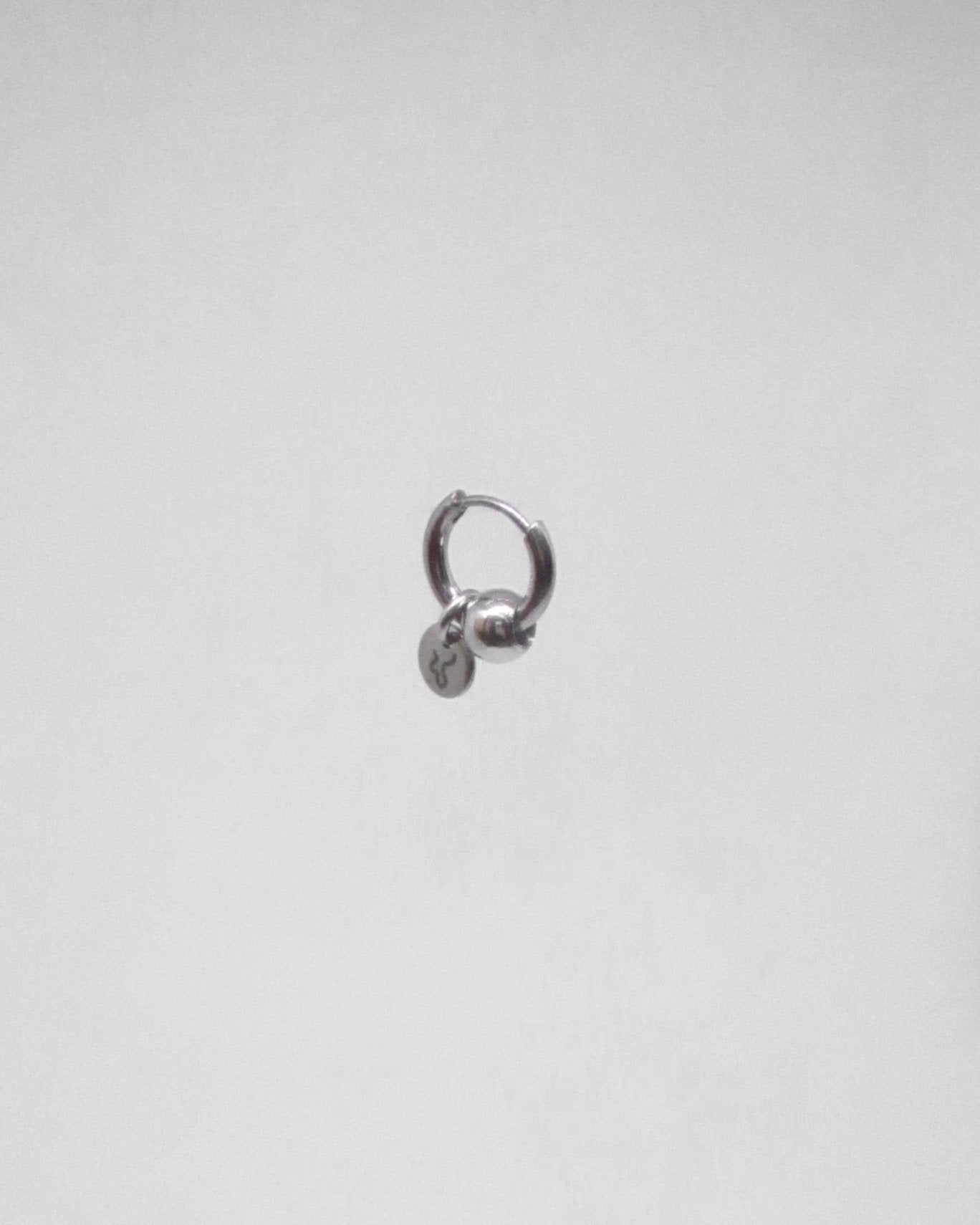 Silver hoop earring on a light gray background