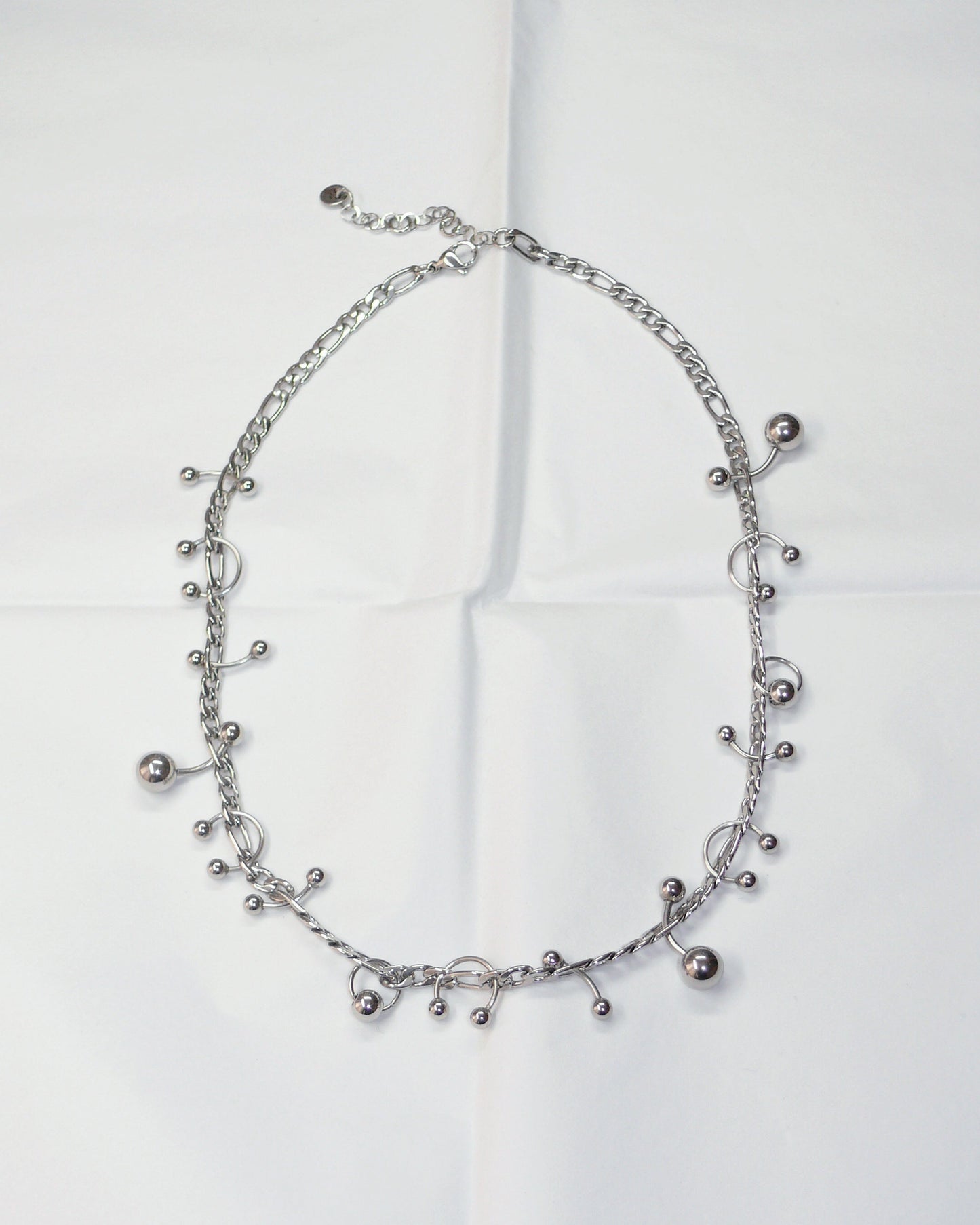 Silver piercing mix necklace on folded paper