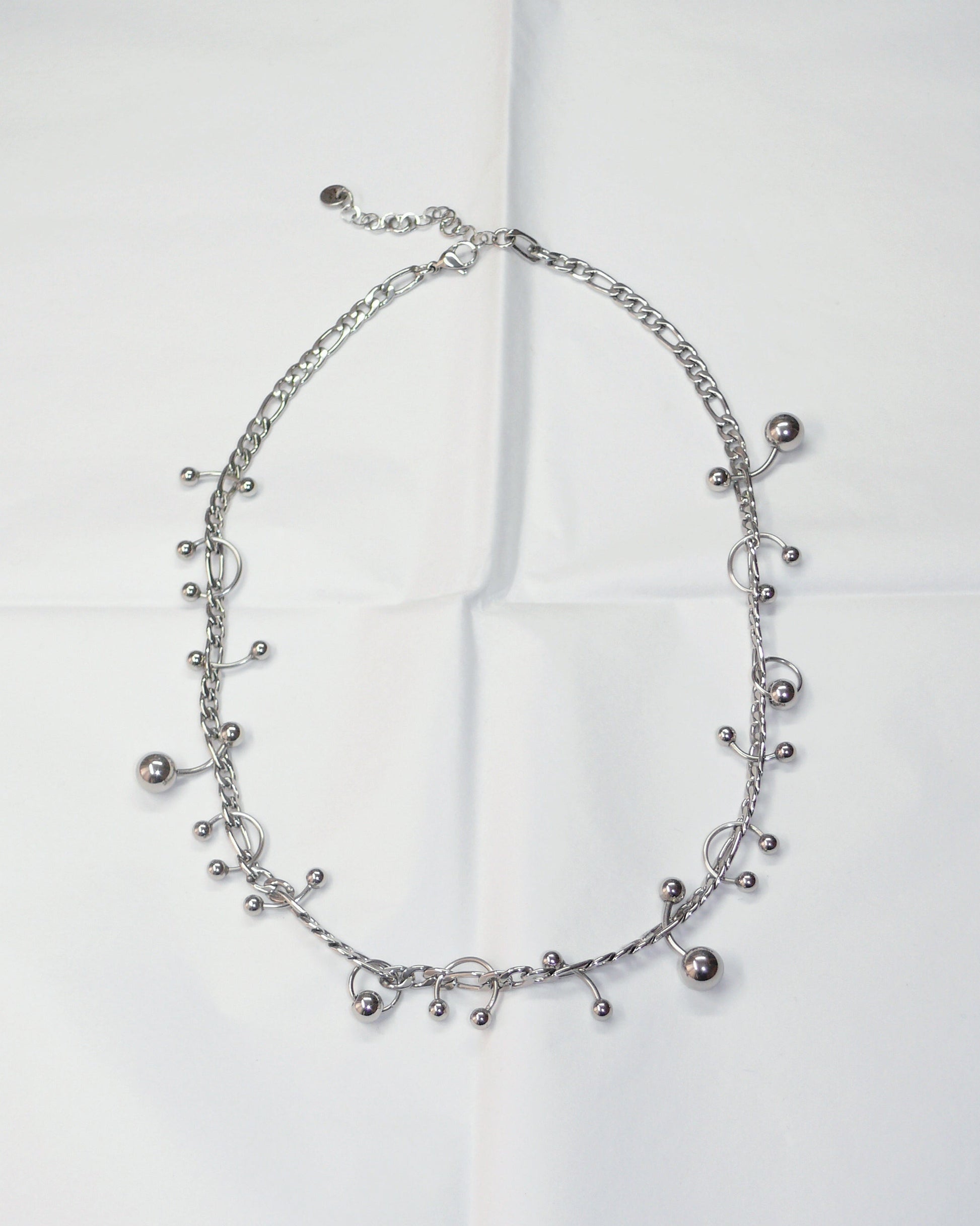 Silver piercing mix necklace on folded paper