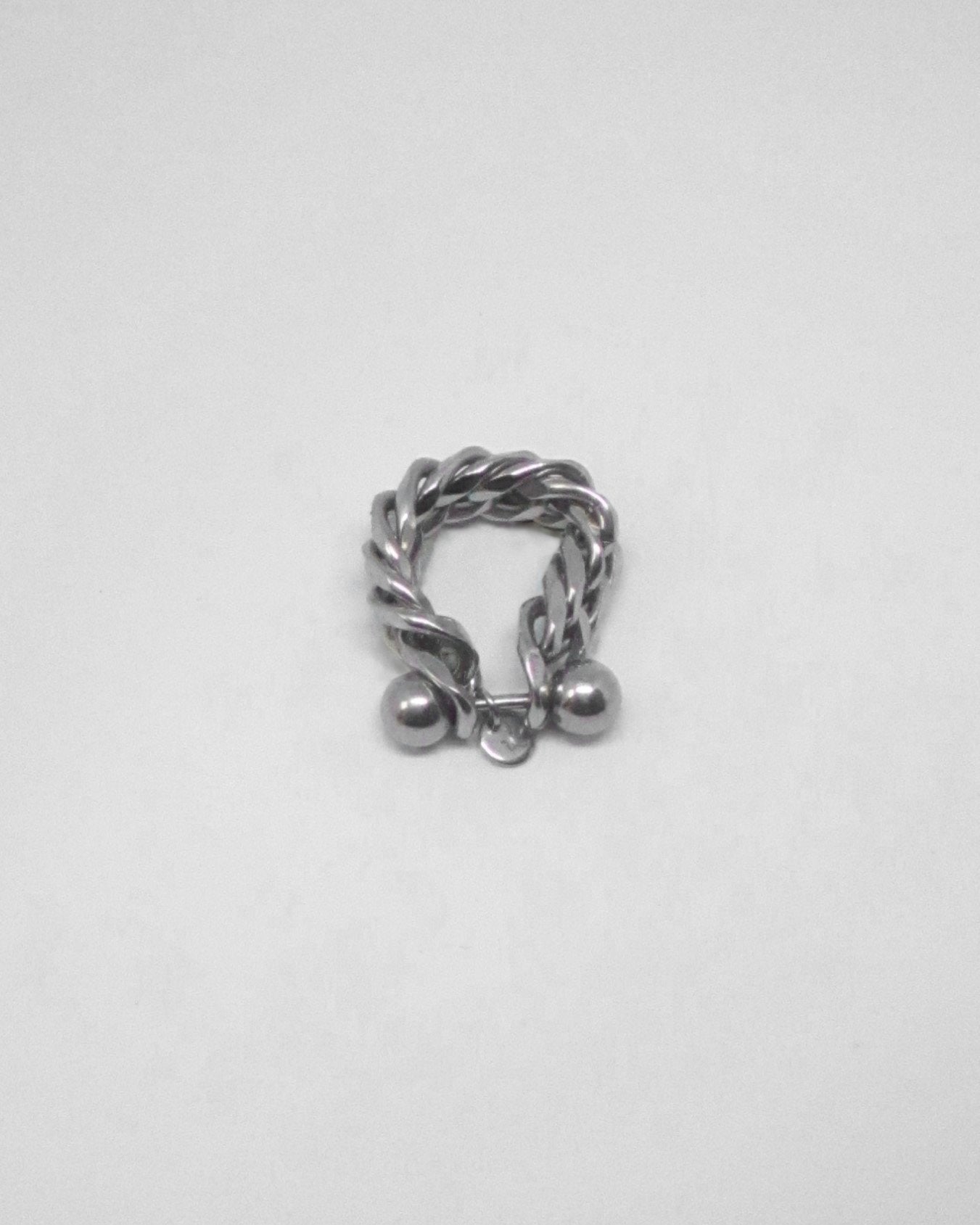 Silver ring with a twisted design and small spherical elements on a light gray background