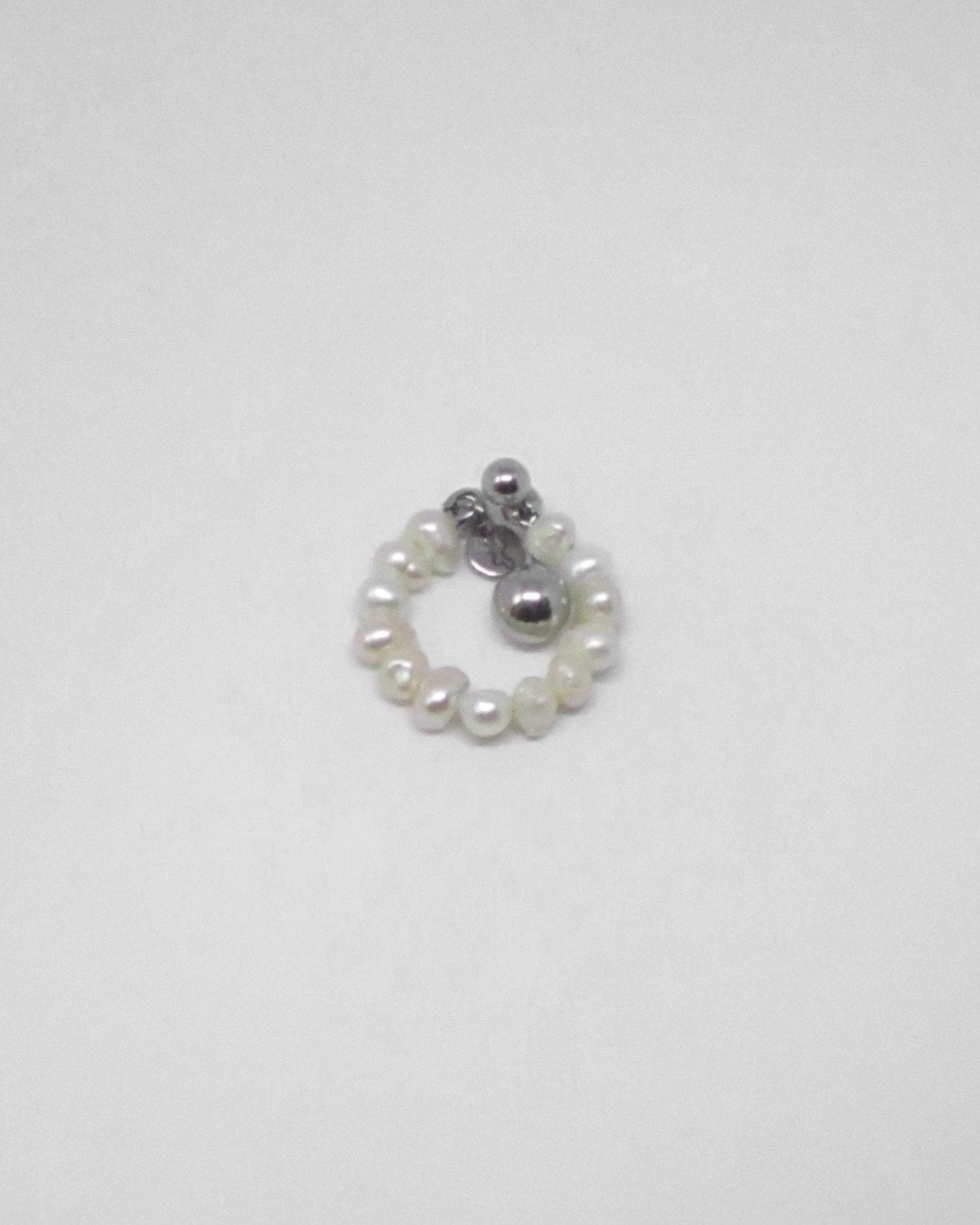 Small ring with pearls and a silver bead on a white background