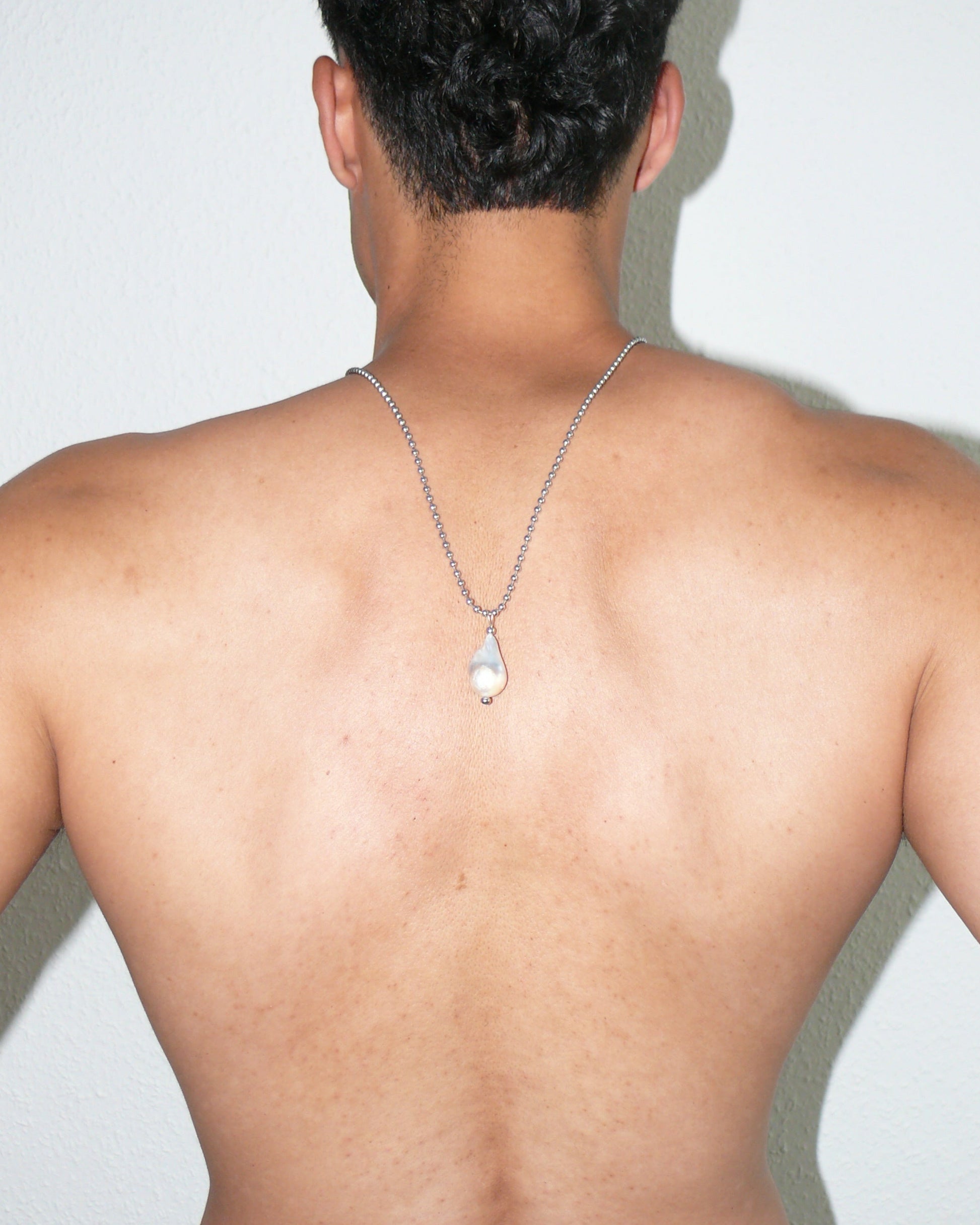 Steel ballchain with baroque pearl pendant close-up portrait on poc model back