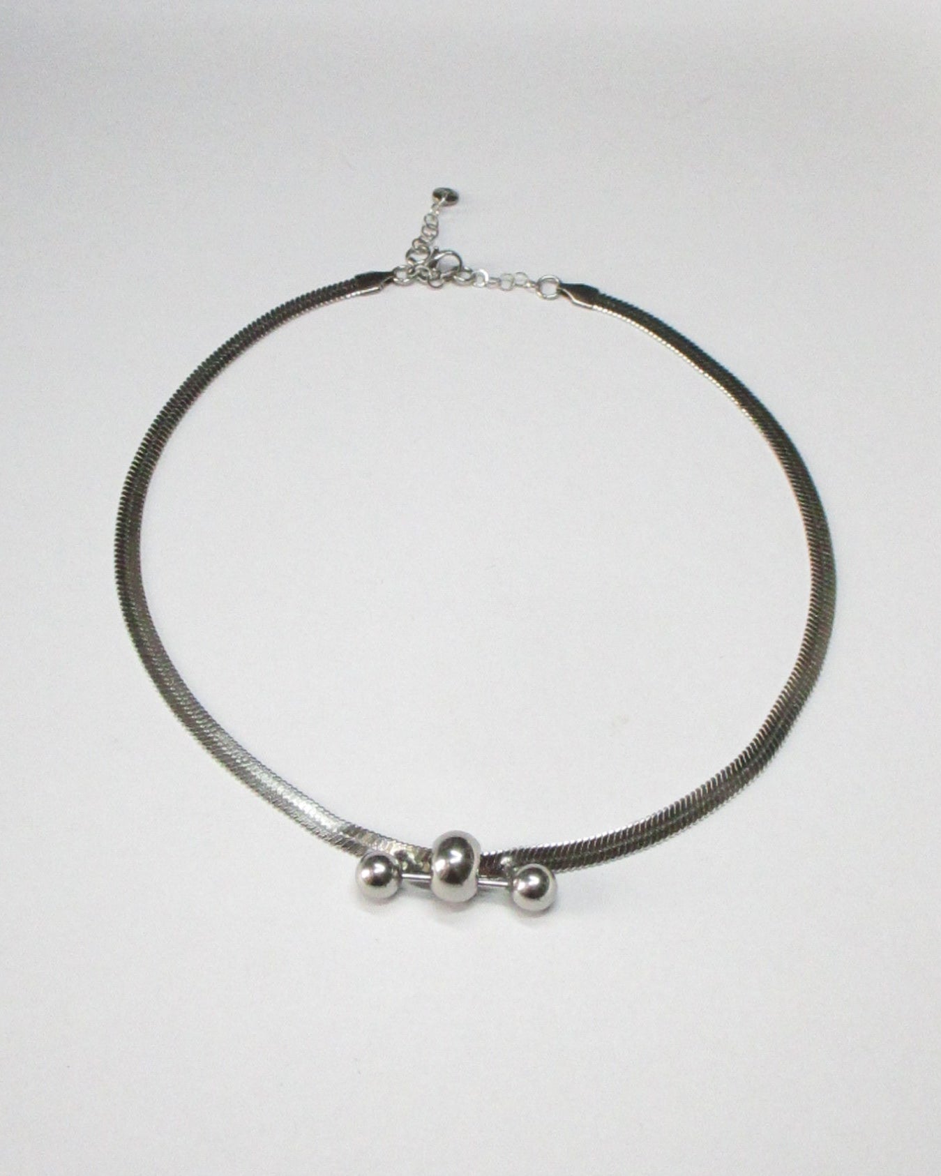 Steel flat chain necklace with central barbell piercing still portrait