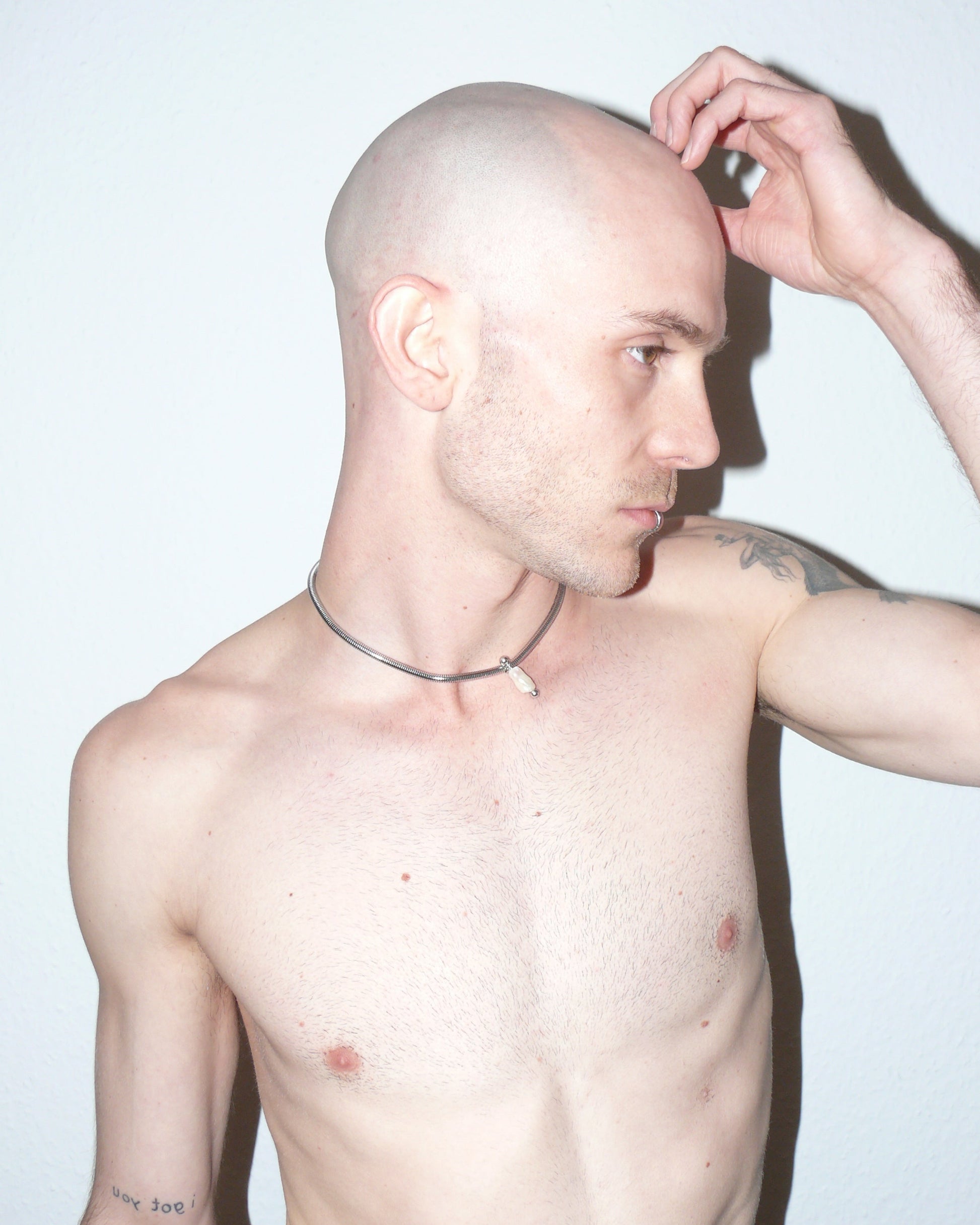 Steel snake chain with pearl pendant decorated with piercing lateral portrait on model