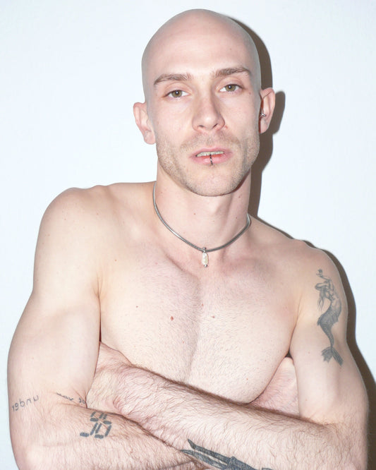 Steel snake chain with pearl pendant decorated with piercing portrait on model with crossed arms